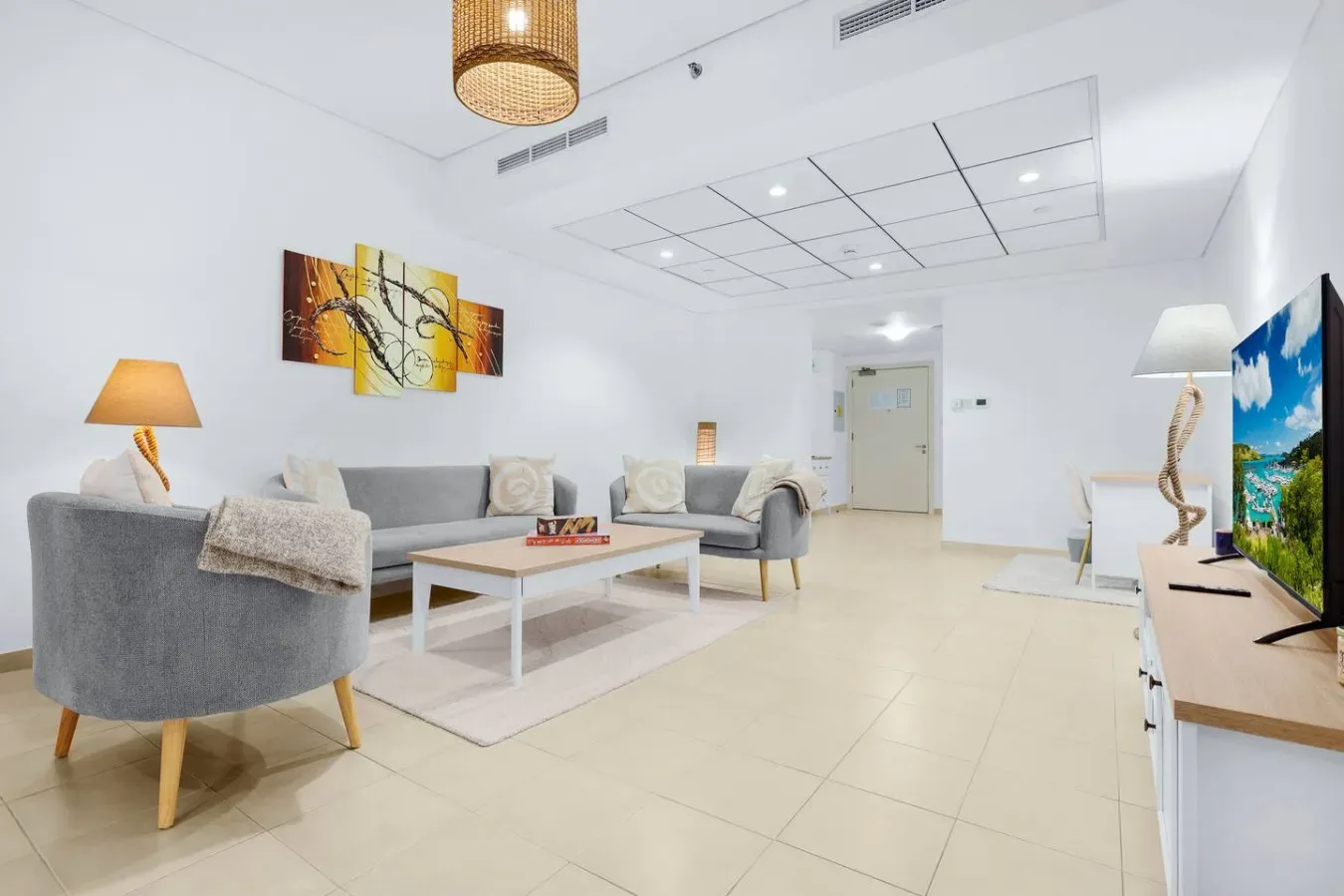 Una sala luminosa con asientos grises, una mesa de centro y un televisor en la pared.