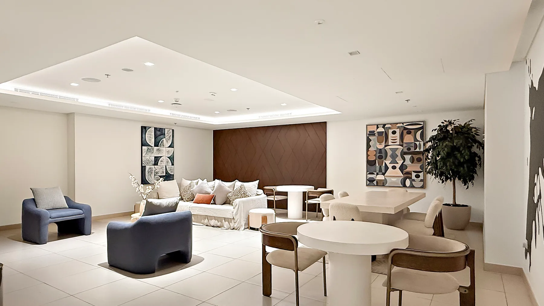 A bright living and dining area with lounge seating, a dining table, and wall art.