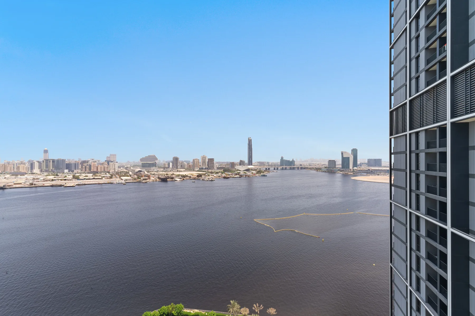 A broad river view with a city skyline and a modern building in the foreground.