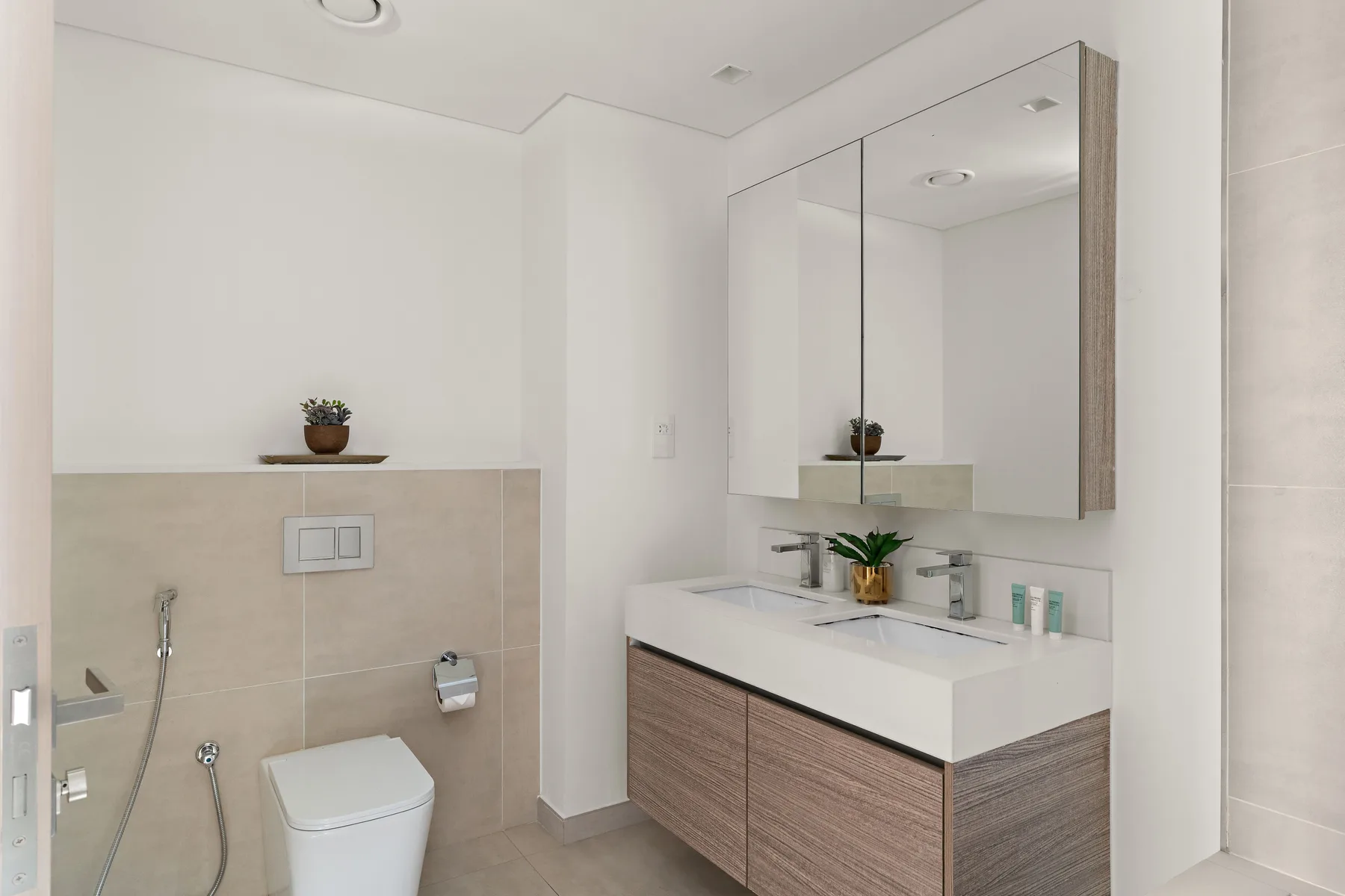 A bright bathroom with a vanity, large mirror, and toilet.