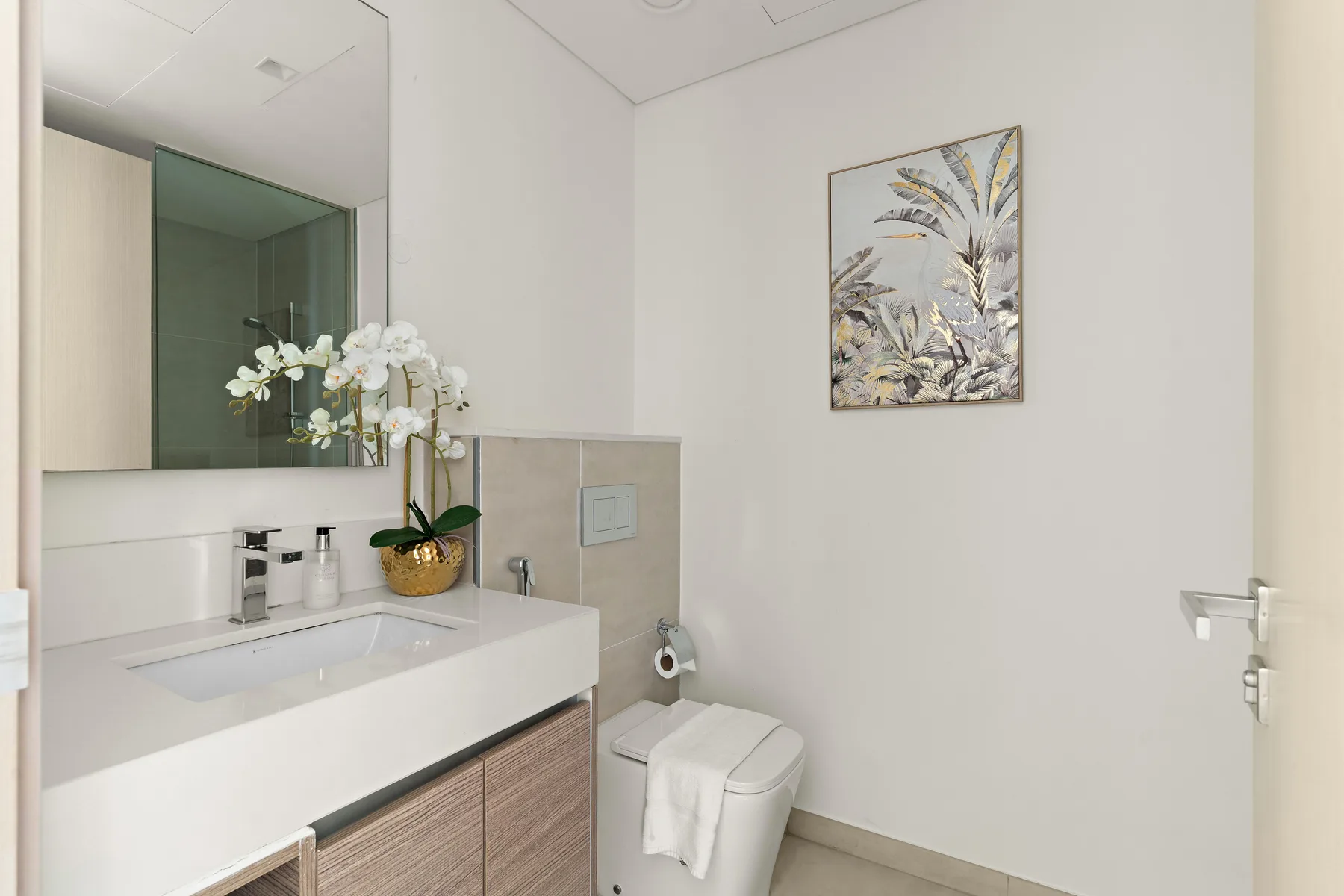 A bathroom with a sink, mirror, and framed botanical artwork.