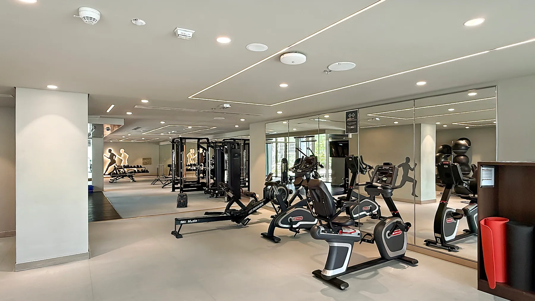 A fitness room with exercise bikes, weight machines, and mirrored walls.