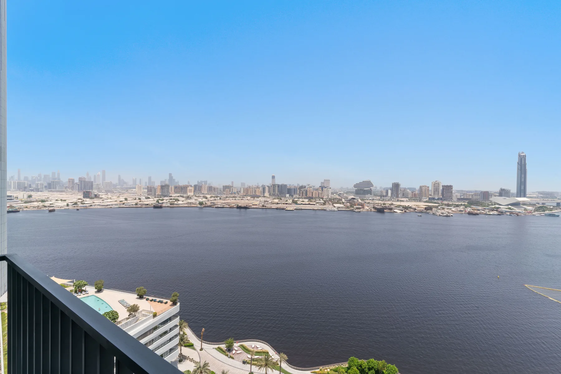 A broad river view overlooks a distant city skyline from a balcony.