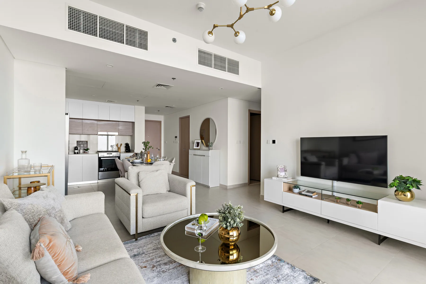 Una sala luminosa con asientos, una mesa de centro redonda y un televisor.
