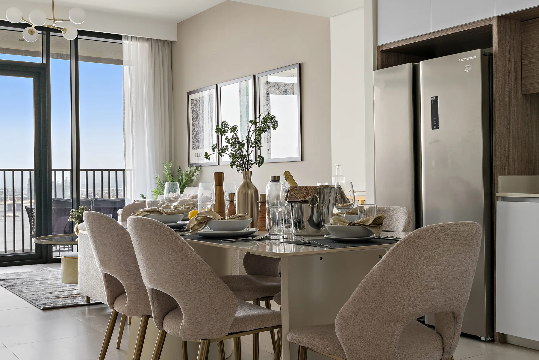 A dining area with a set table and large windows opening onto a balcony.
