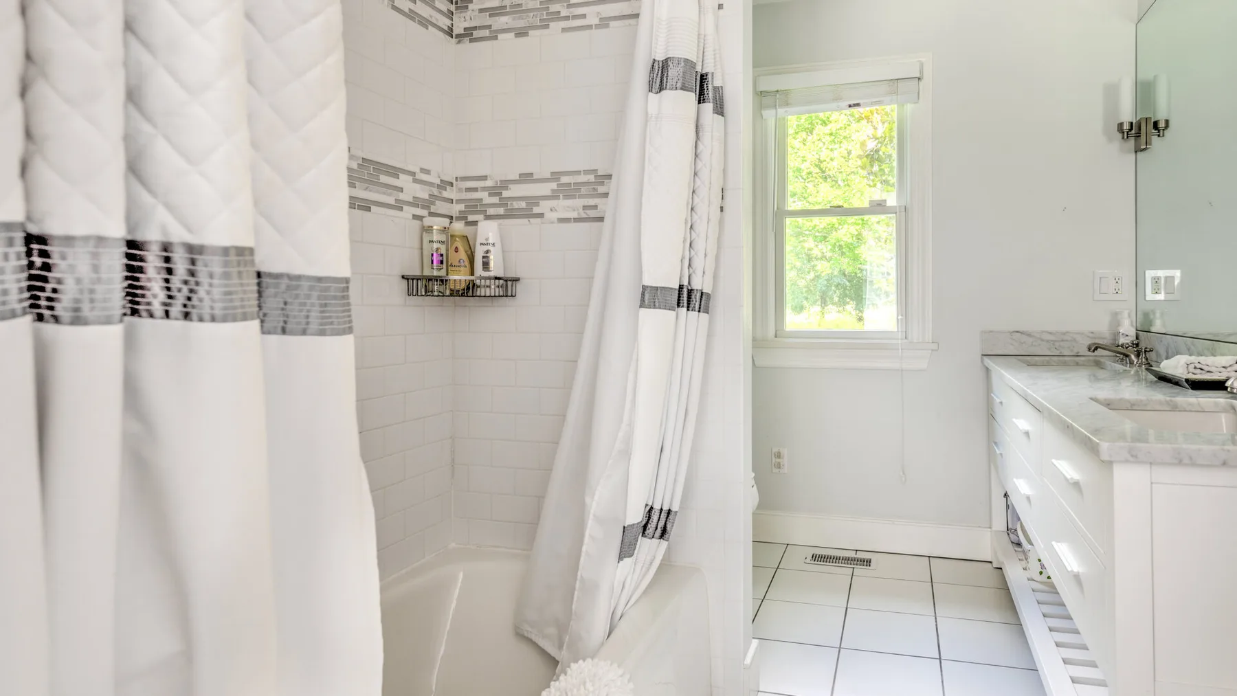 Un baño luminoso con una ducha revestida de azulejos y una ventana.