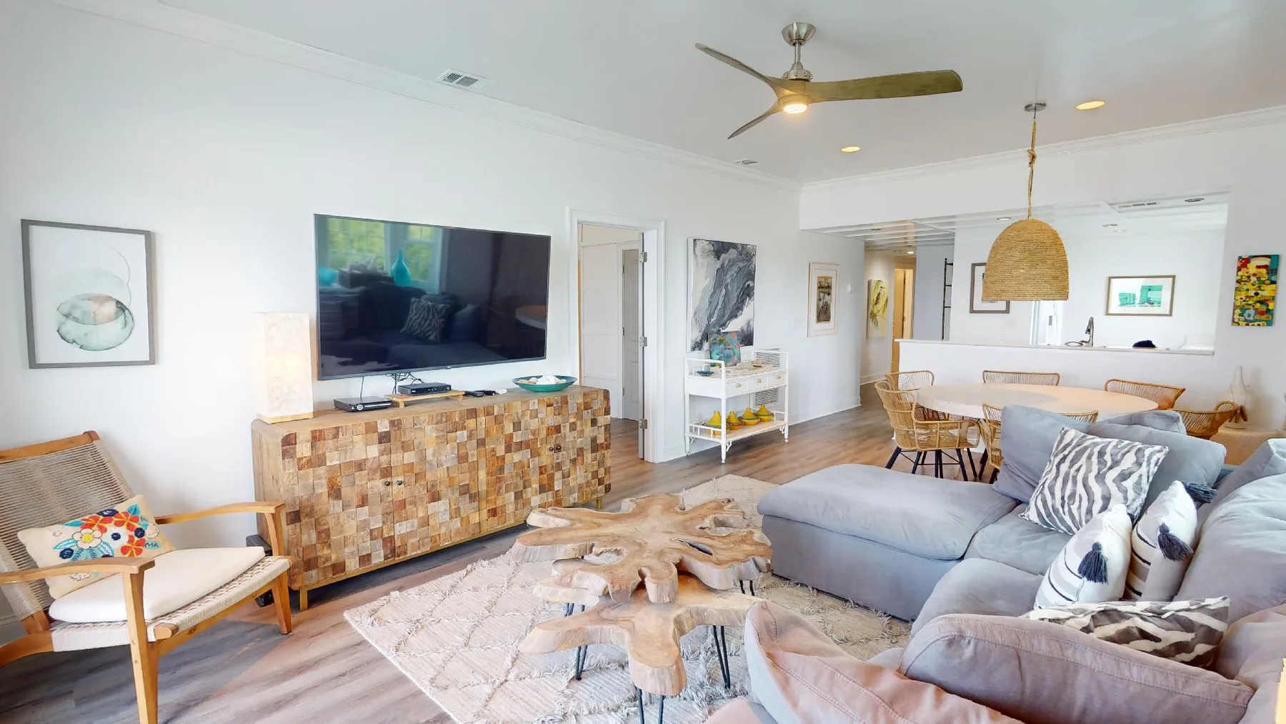 A bright living room with a sectional sofa and a wall-mounted television.