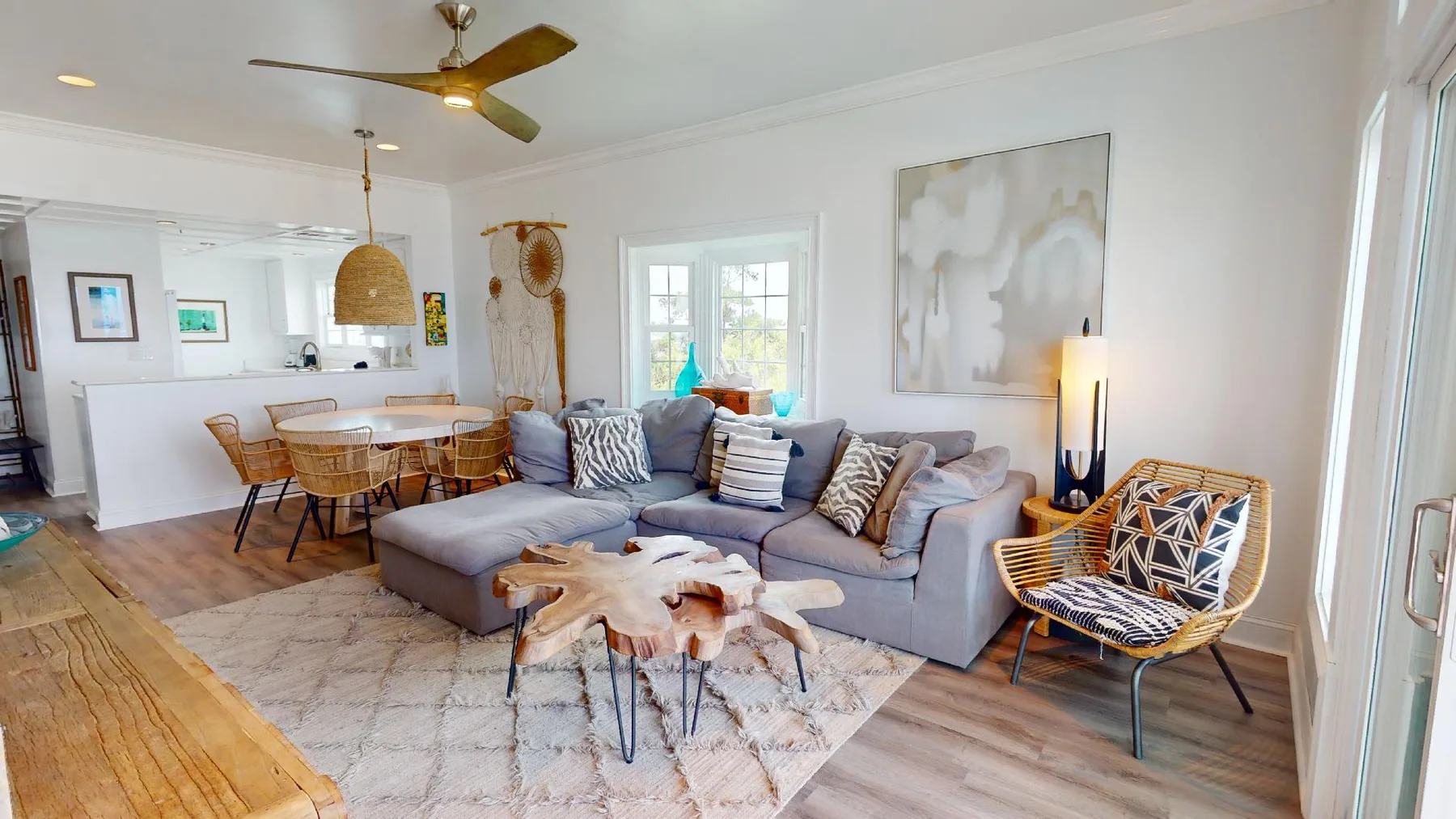A bright living room with seating, a dining area, and large windows.