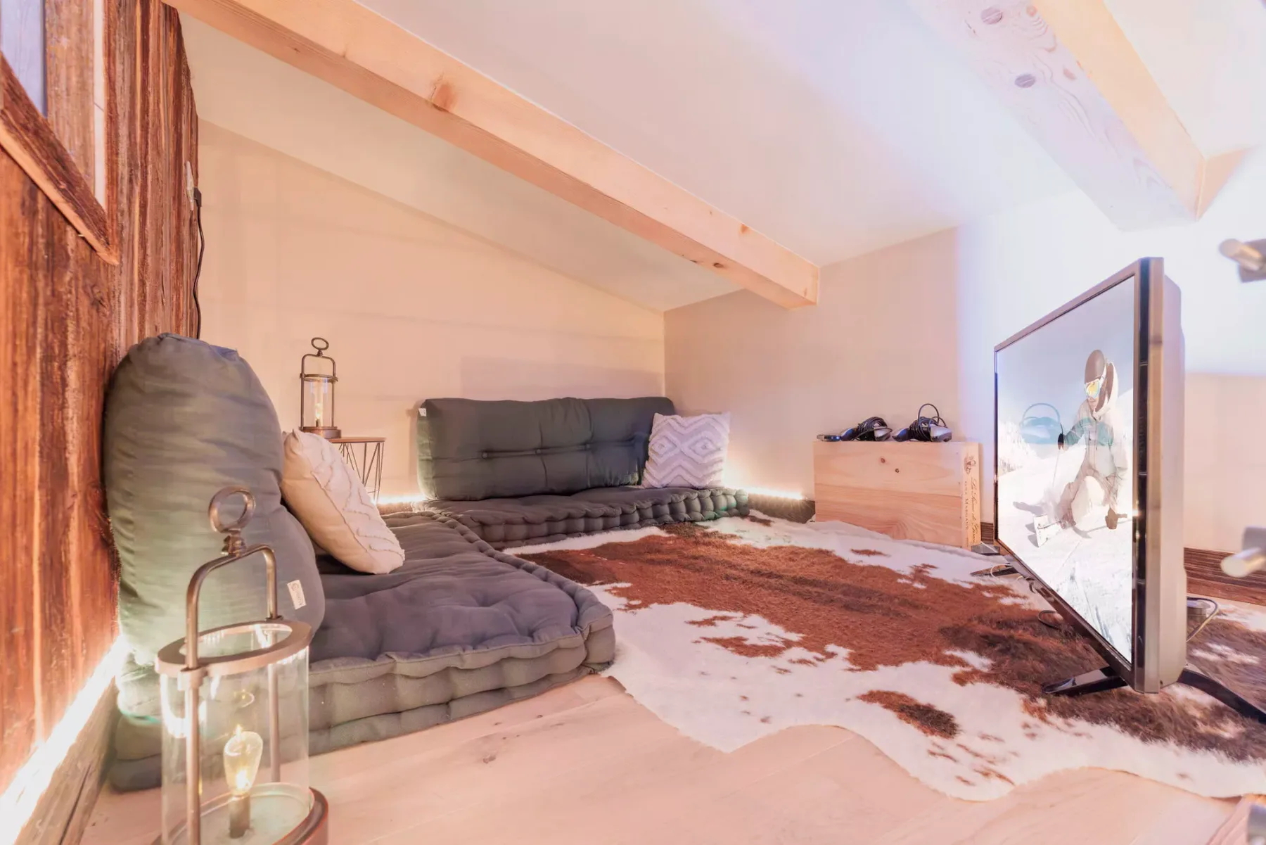 A cozy attic lounge with low seating, a patterned rug, and a large framed artwork.