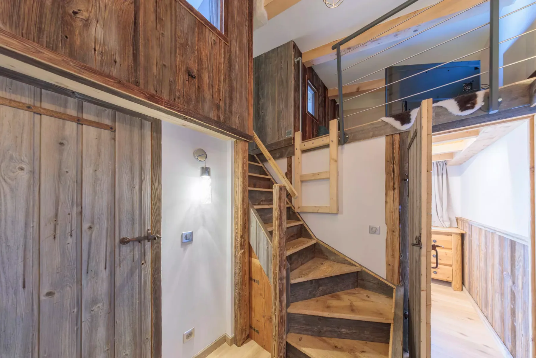 A rustic wood interior with a staircase leading to an upper level.
