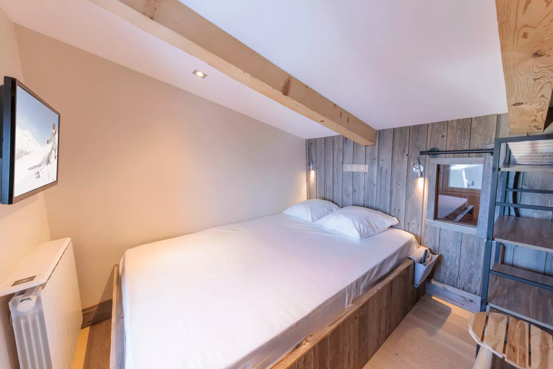 A bedroom with a large bed beneath exposed wooden beams.