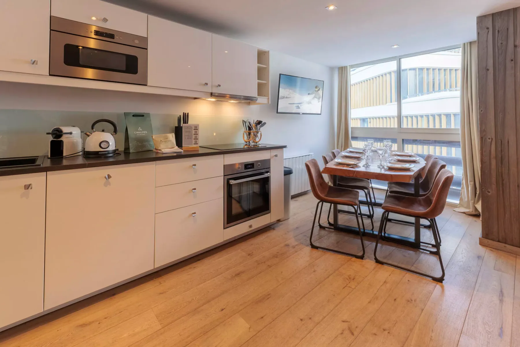 Una luminosa cocina con comedor y una mesa junto a grandes ventanas.