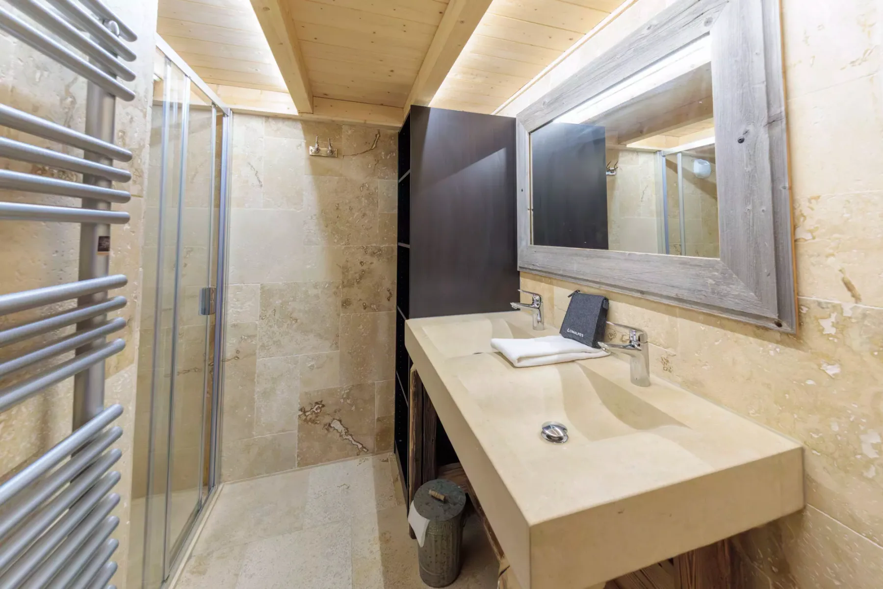 A bathroom with a glass shower and a long vanity beneath a wide mirror.
