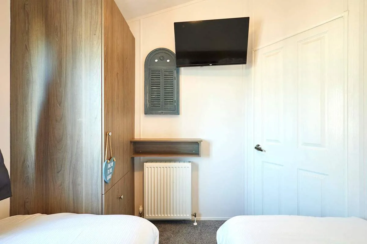 Un dormitorio con camas, un televisor y un radiador.