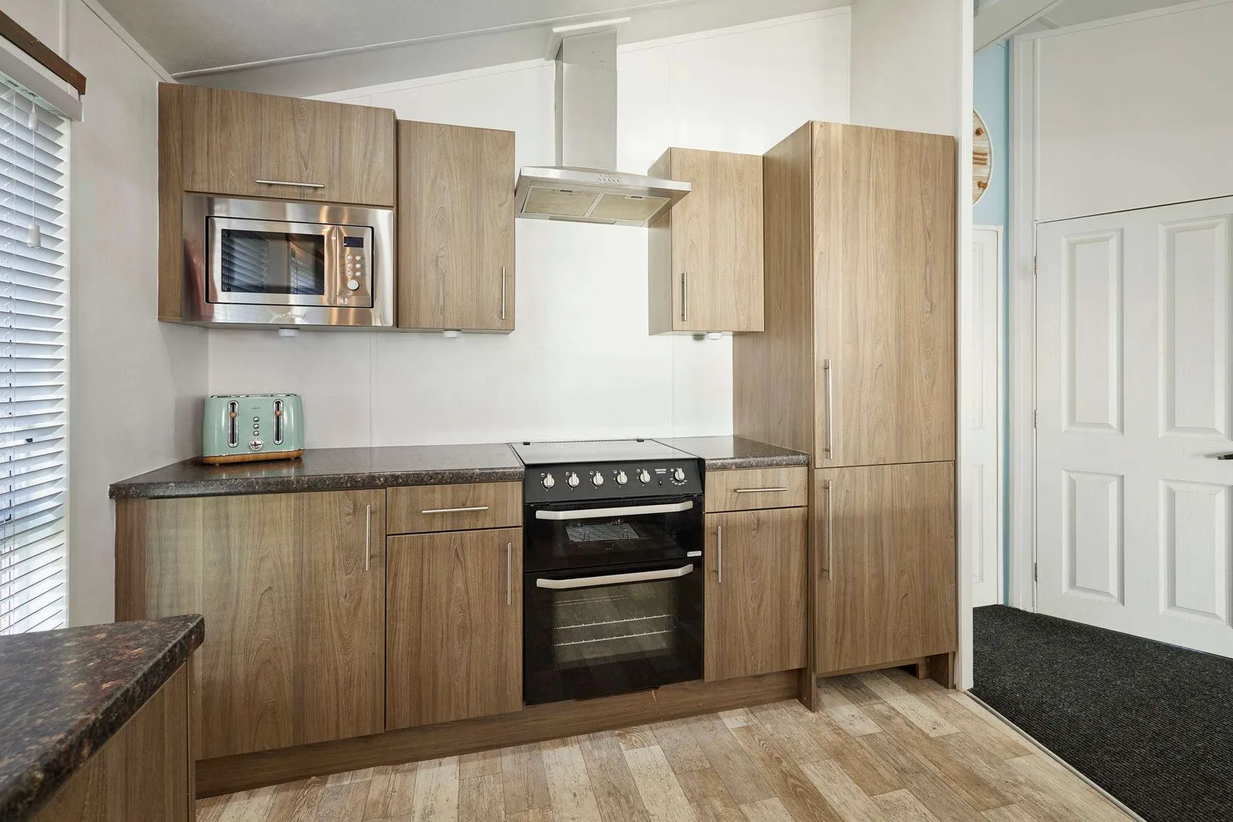 Una cocina moderna con gabinetes de acabado madera, microondas y estufa.