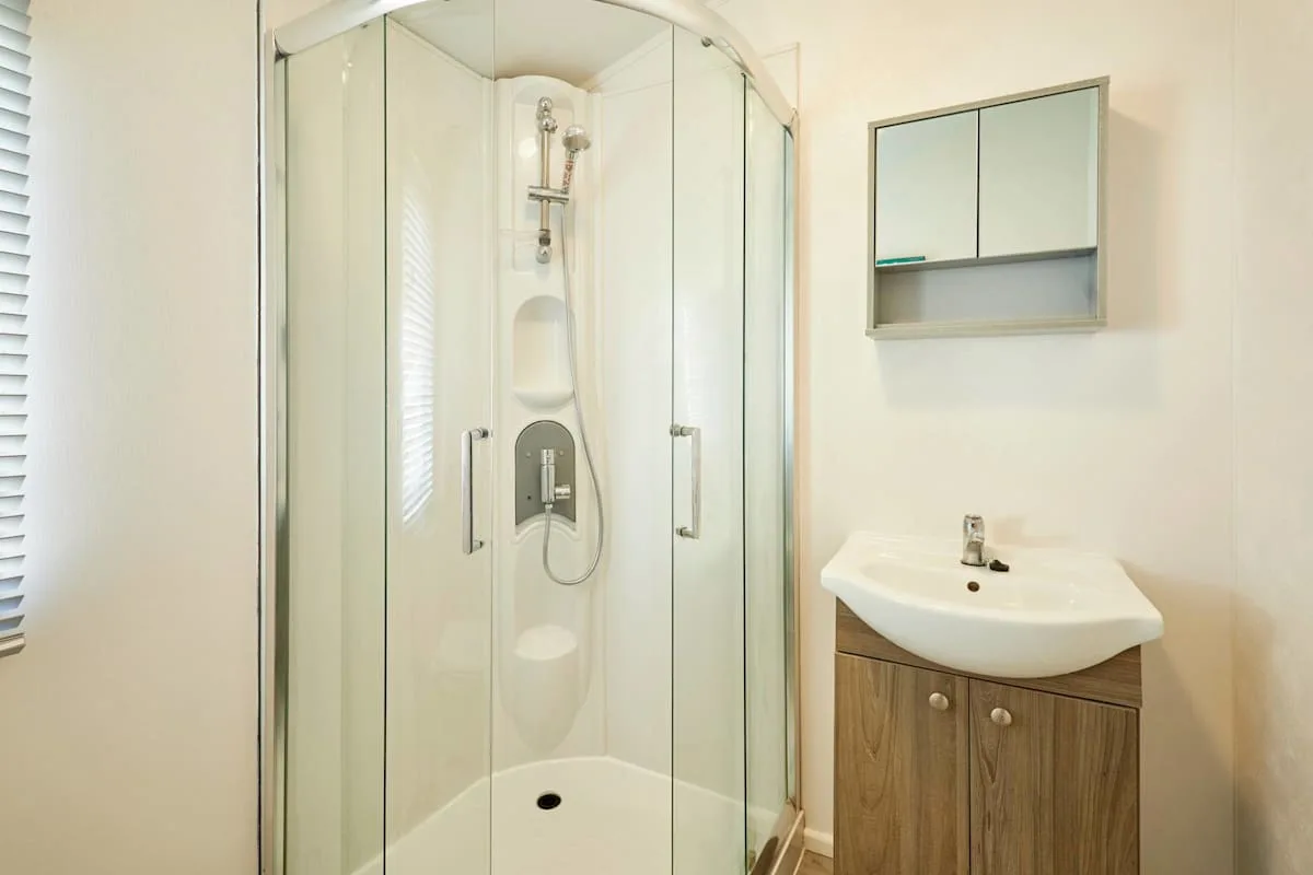 Un baño luminoso con ducha y un mueble de lavabo.