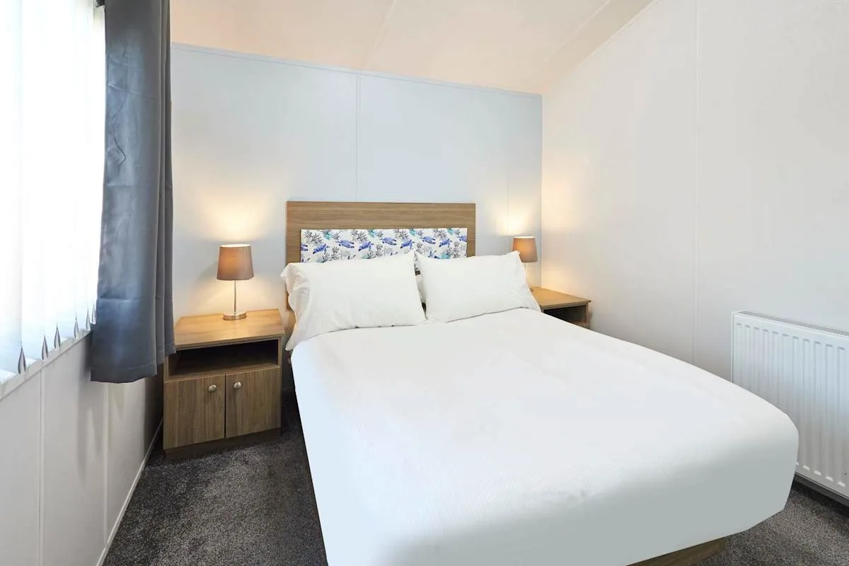 Dormitorio con cama doble, mesitas de noche y lámparas.