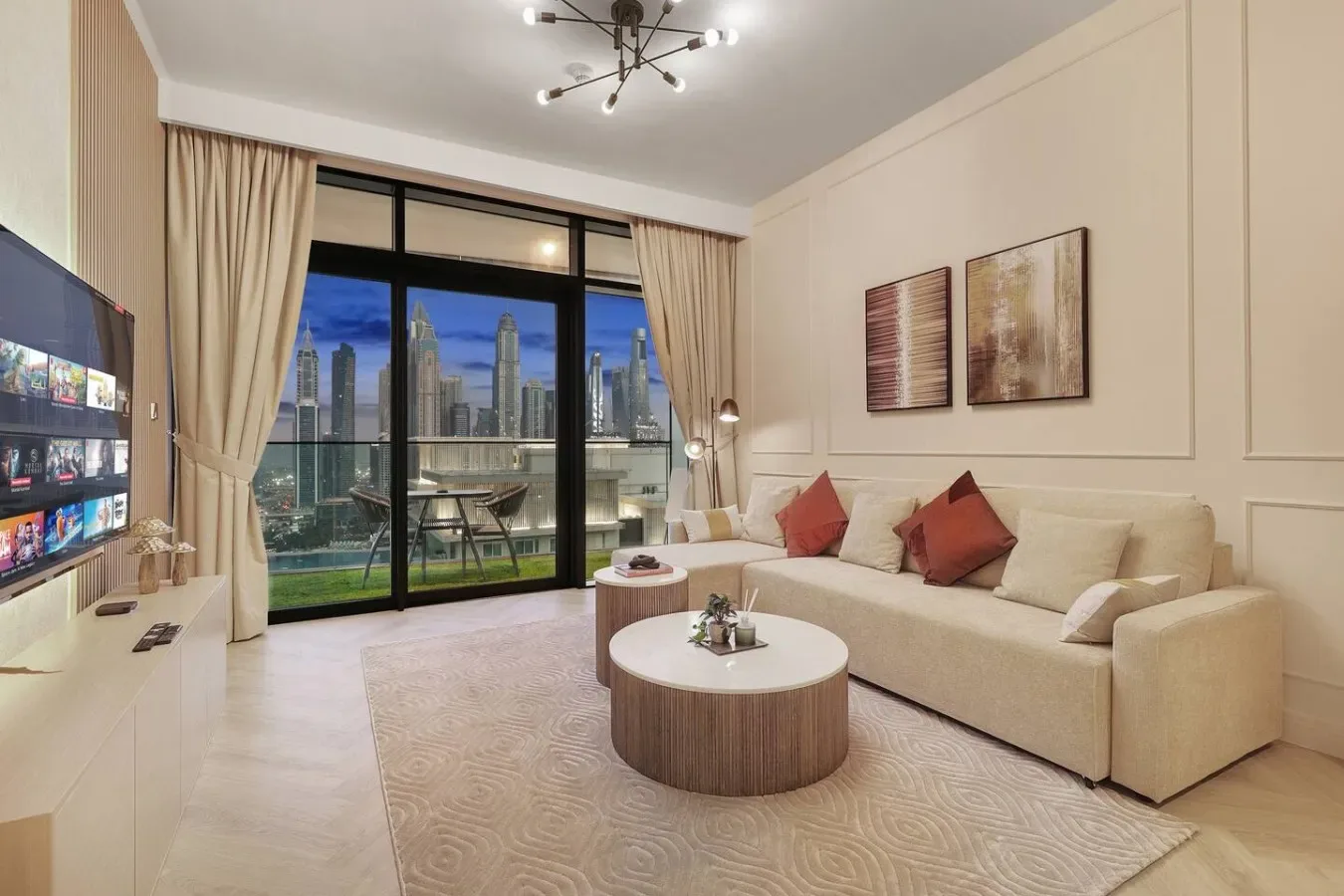Una sala de estar luminosa con asientos beige y grandes ventanas con vistas a la ciudad.