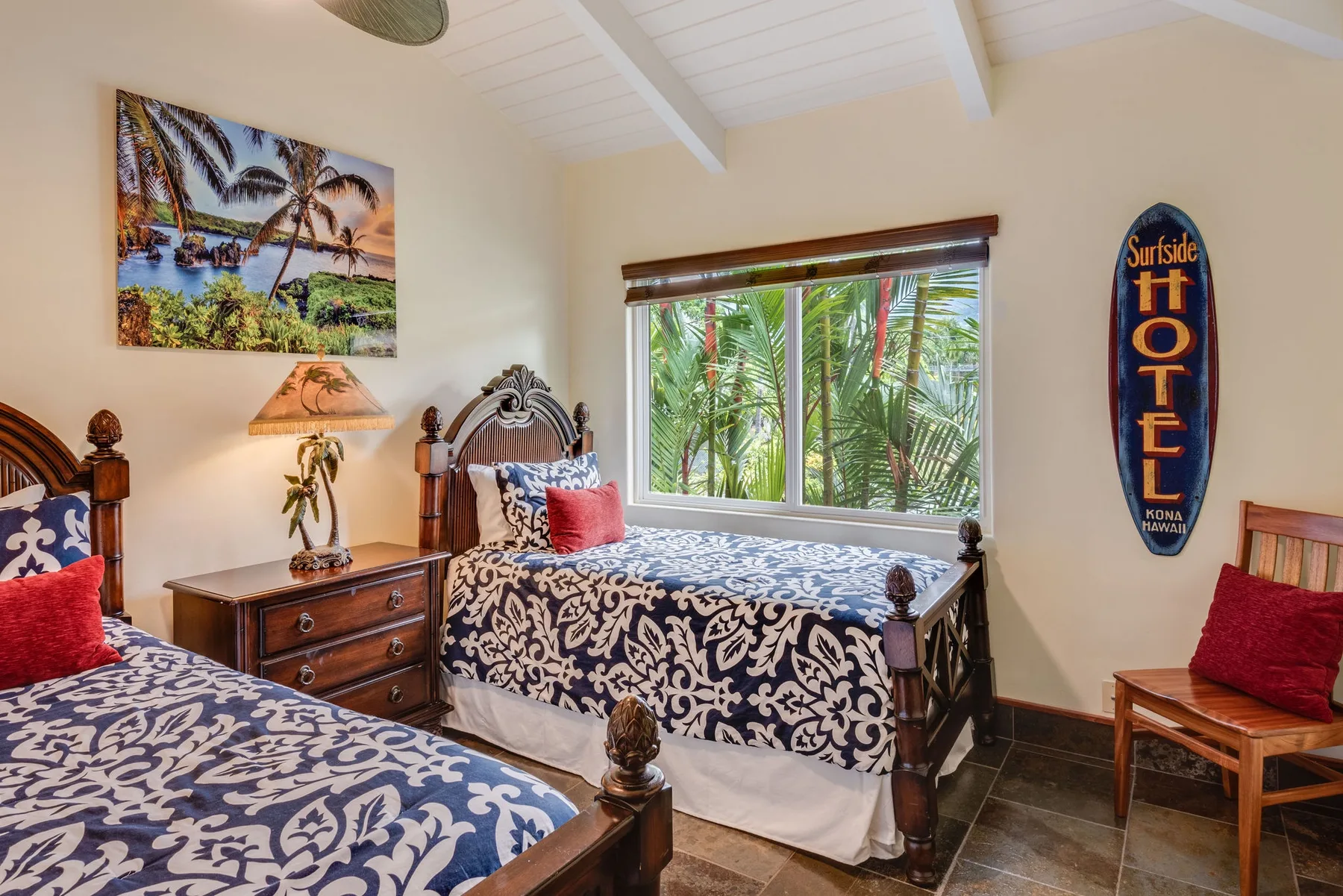 Un dormitorio con dos camas, una ventana y plantas tropicales en el exterior.