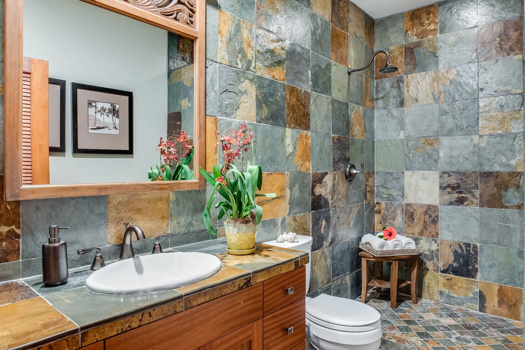Un baño revestido de azulejos con lavabo, espejo, inodoro y ducha.