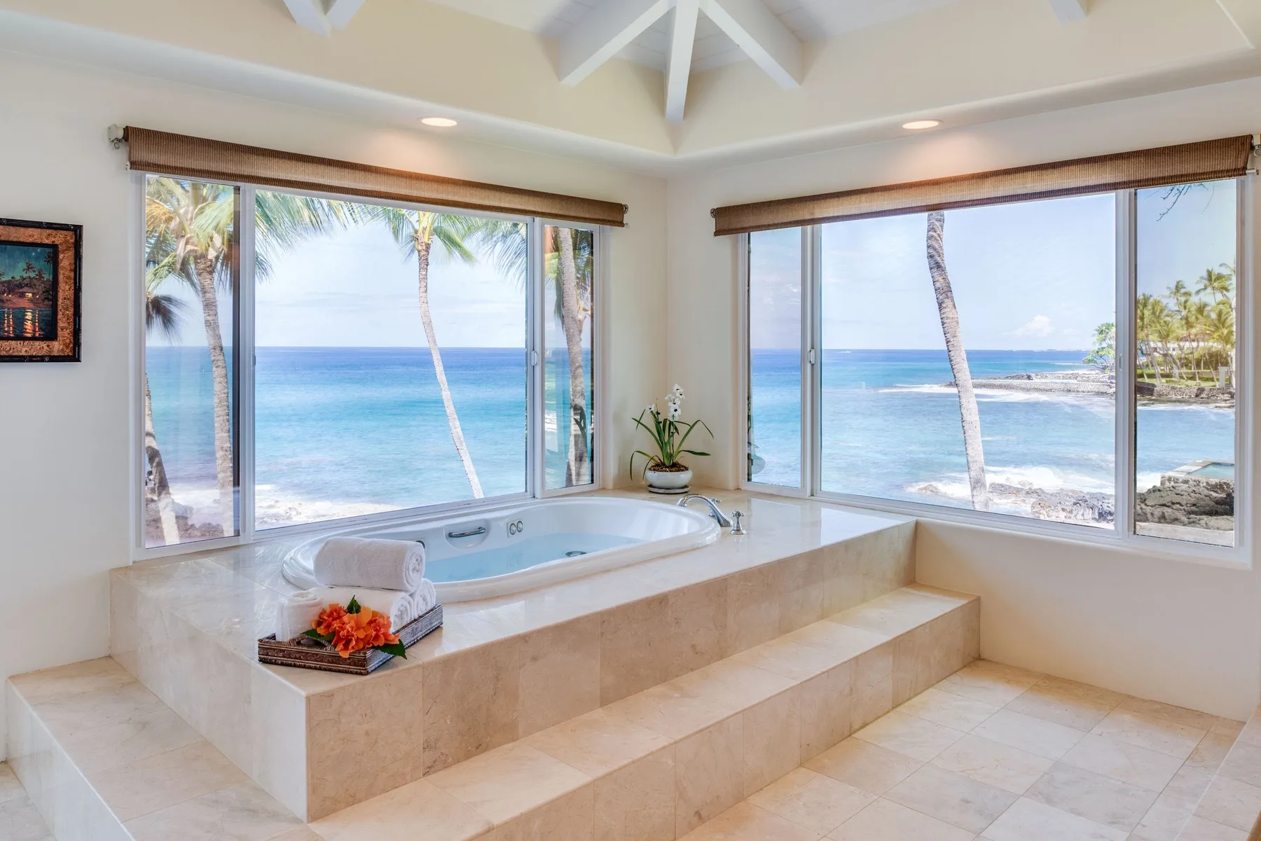 Un baño alicatado con bañera junto a grandes ventanas con vistas al océano.