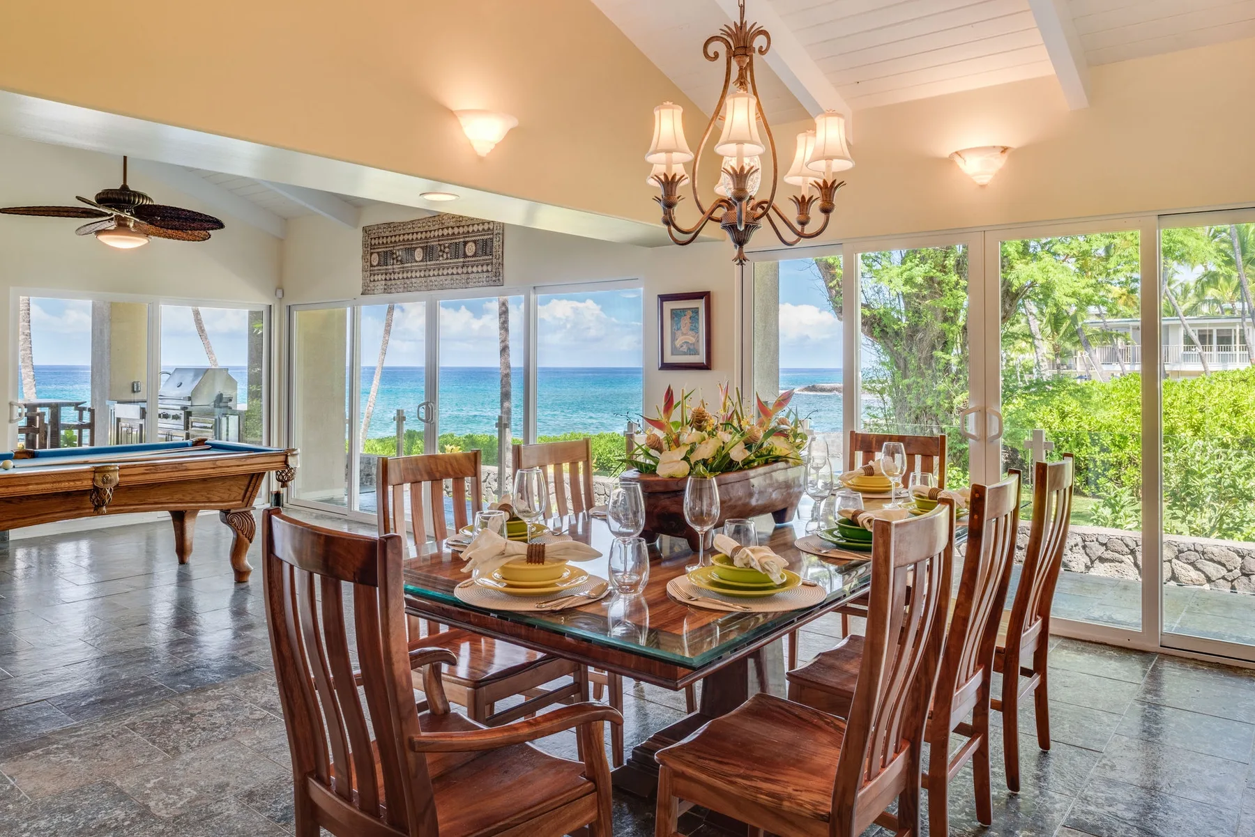 Un comedor con una mesa de vidrio y grandes ventanas con vista al mar.