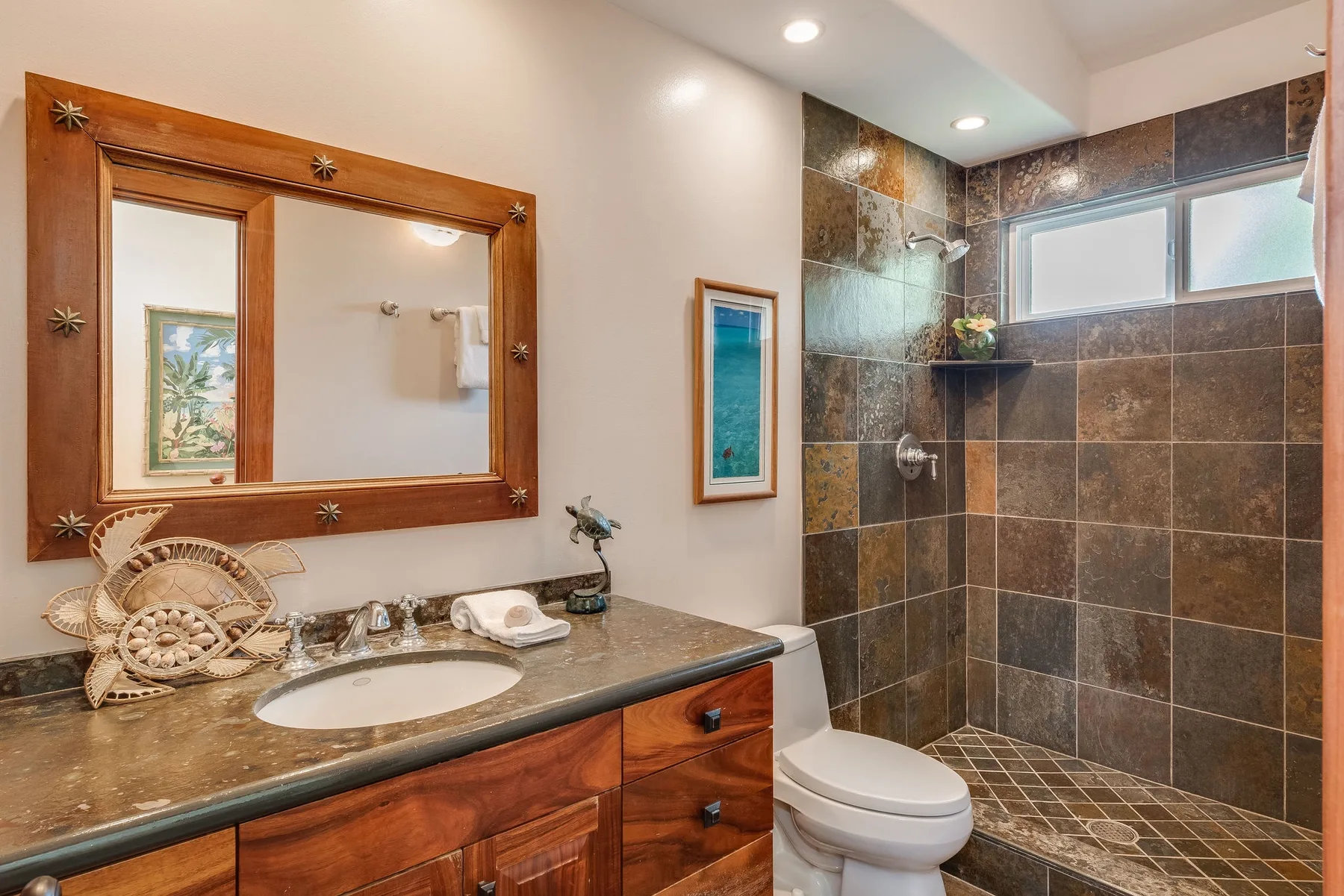 Un baño con tocador de madera, espejo, inodoro y ducha revestida de azulejos.