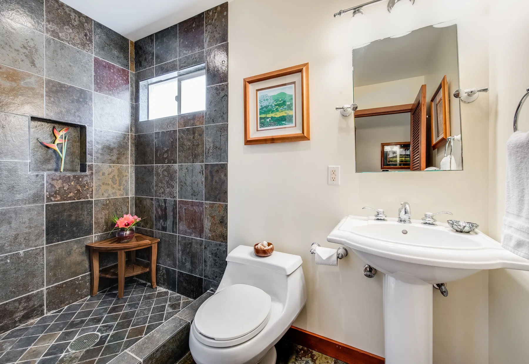 Un baño con ducha alicatada, inodoro y lavabo con pedestal.