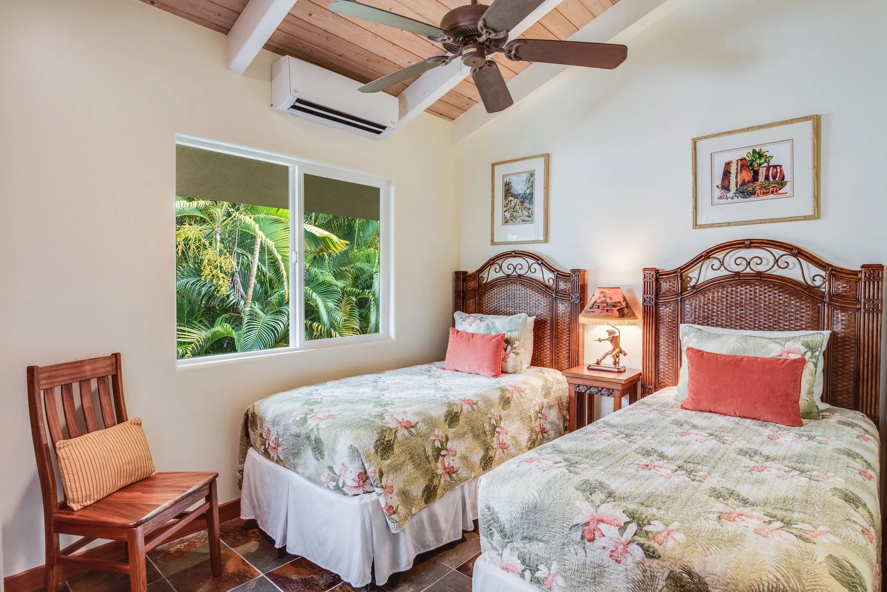 Un dormitorio con dos camas, ropa de cama floral y una ventana con vista a la vegetación.