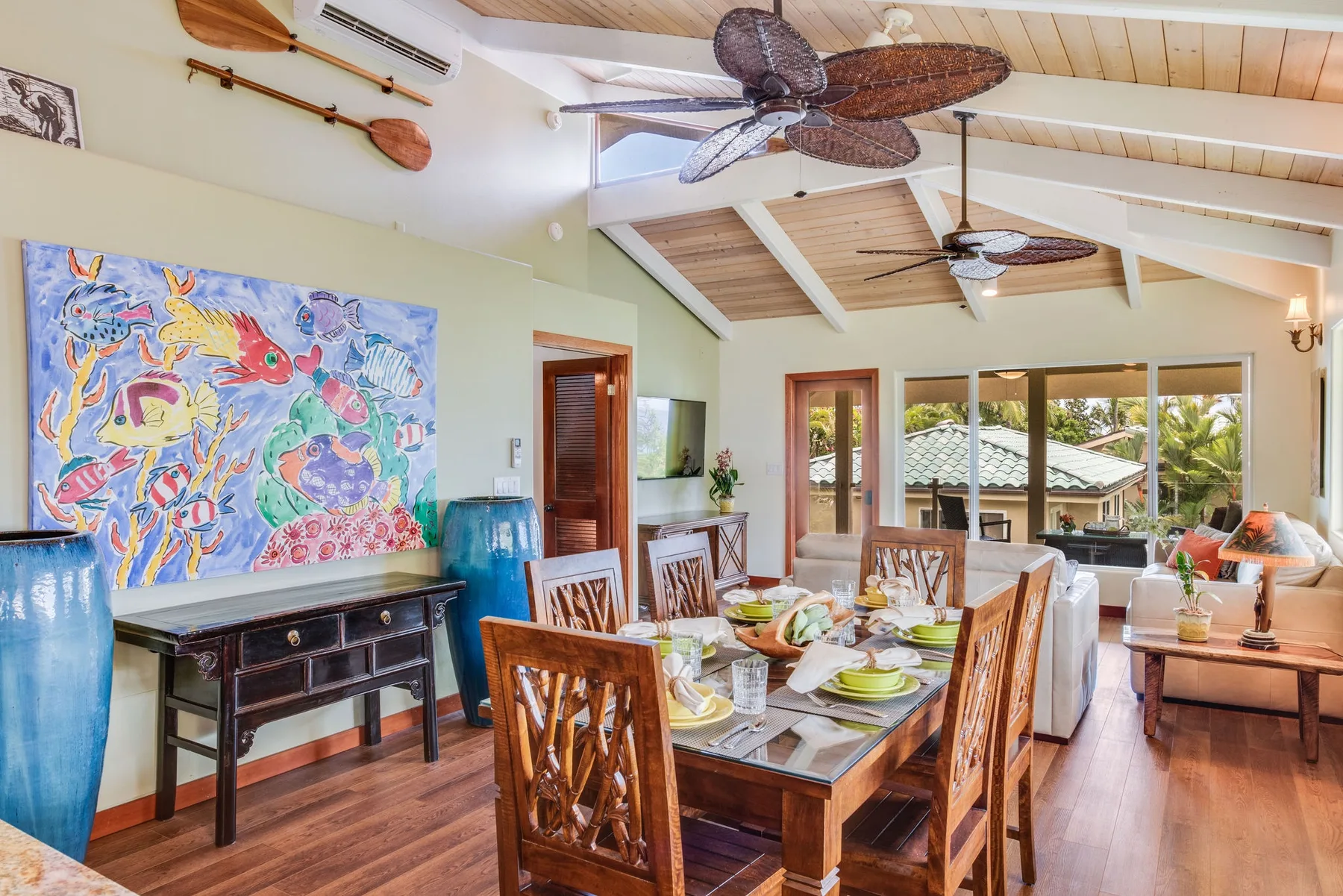 Un espacio abierto de comedor y sala con una mesa de madera junto a grandes ventanales.