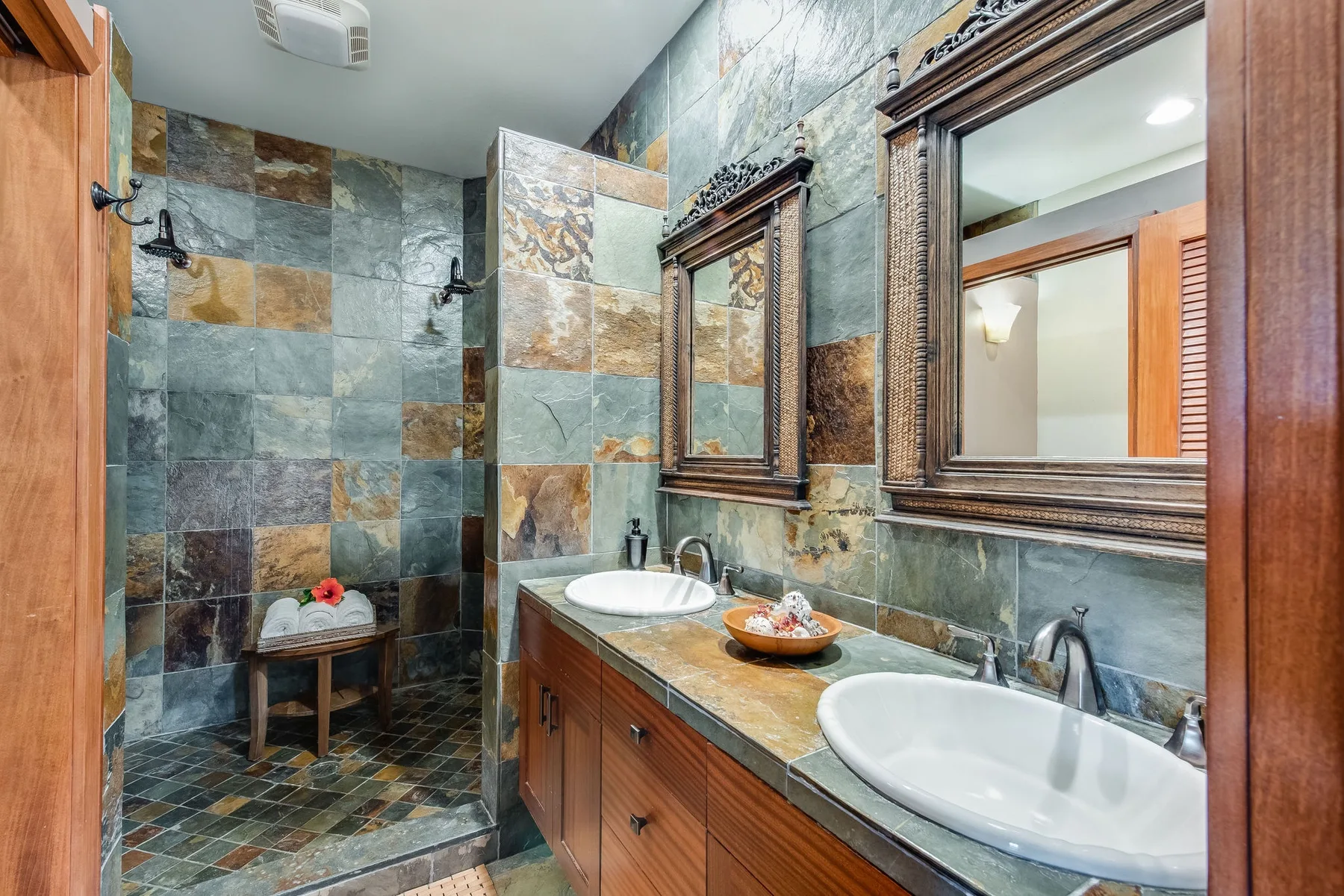 Un baño alicatado con un tocador largo, dos lavabos y espejos en la pared.
