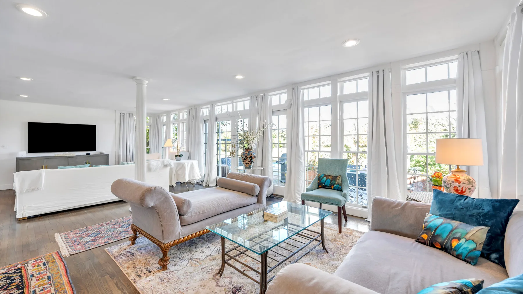 A bright living room with seating arranged around a glass coffee table.