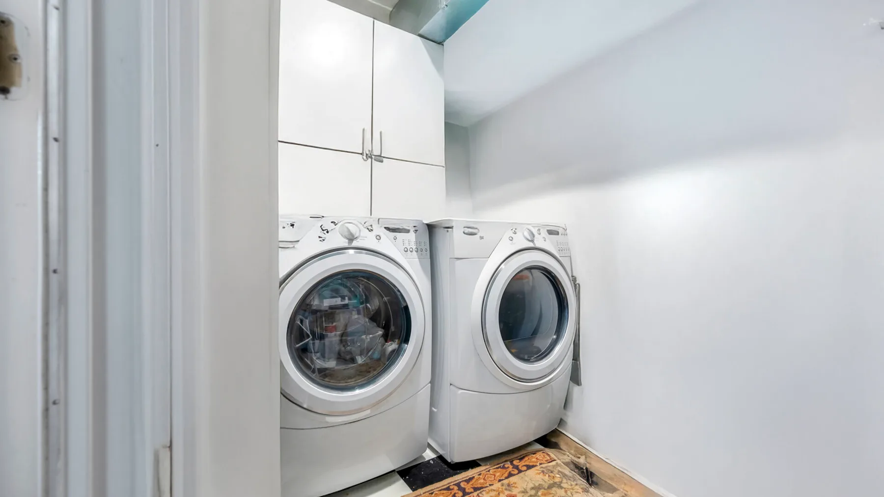 A laundry area with two front-loading washing machines beneath overhead cabinets.