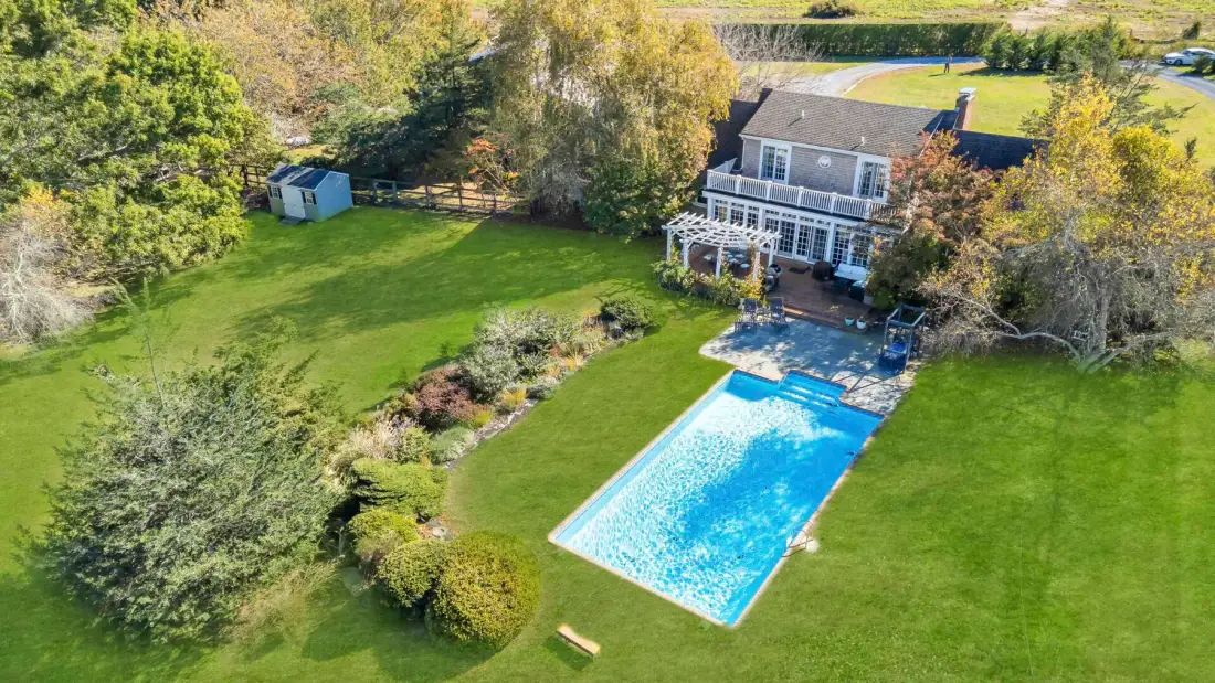 Vista aérea de una casa, un jardín y una piscina azul brillante.