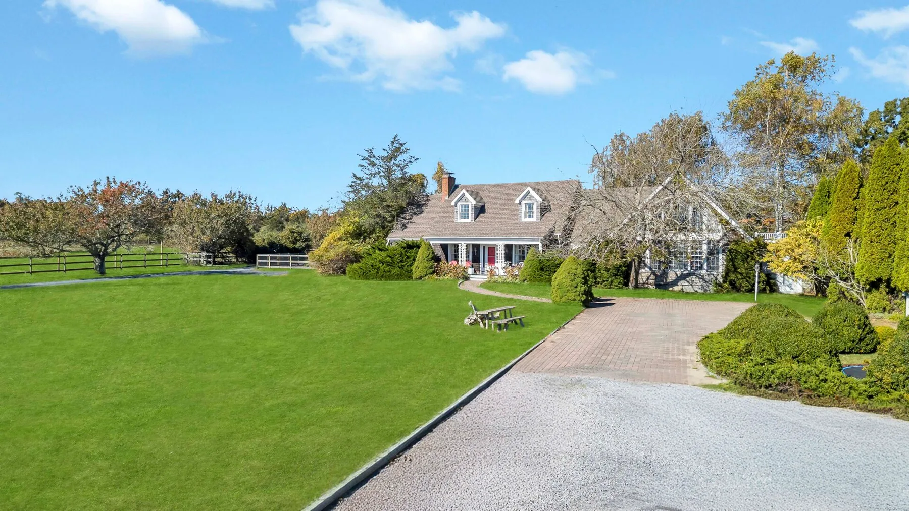 A landscaped property with a broad lawn, paved driveway, and house.