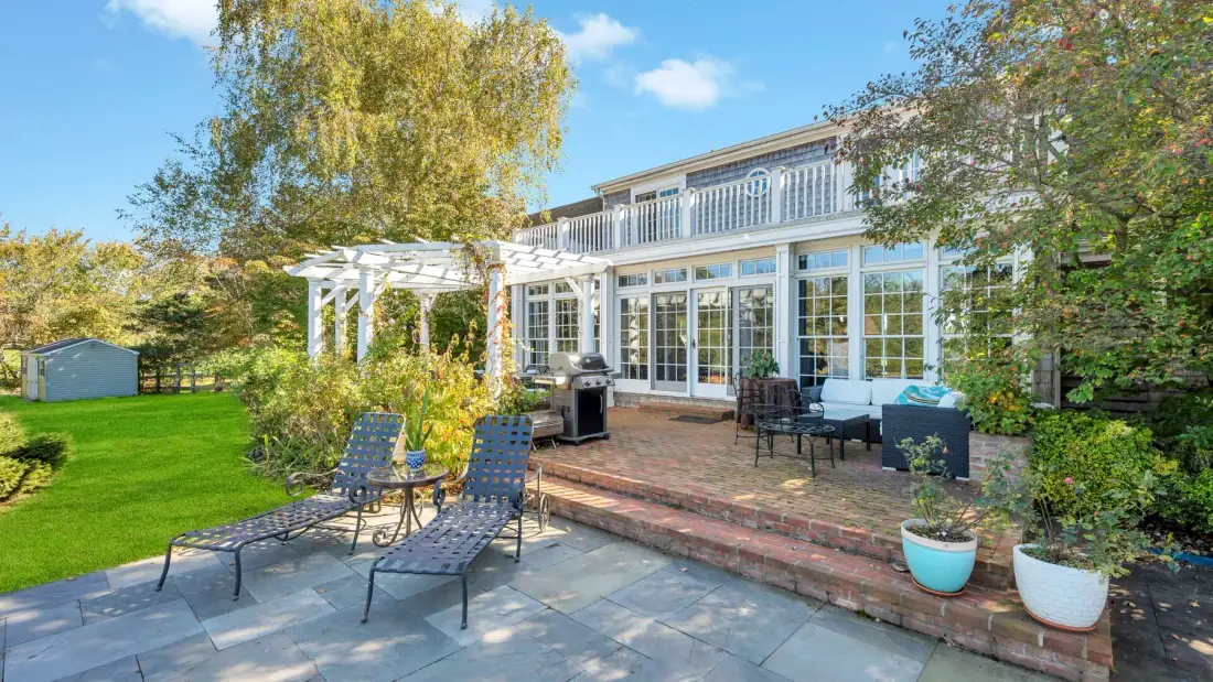 A garden patio with outdoor seating beside a glass-fronted house.