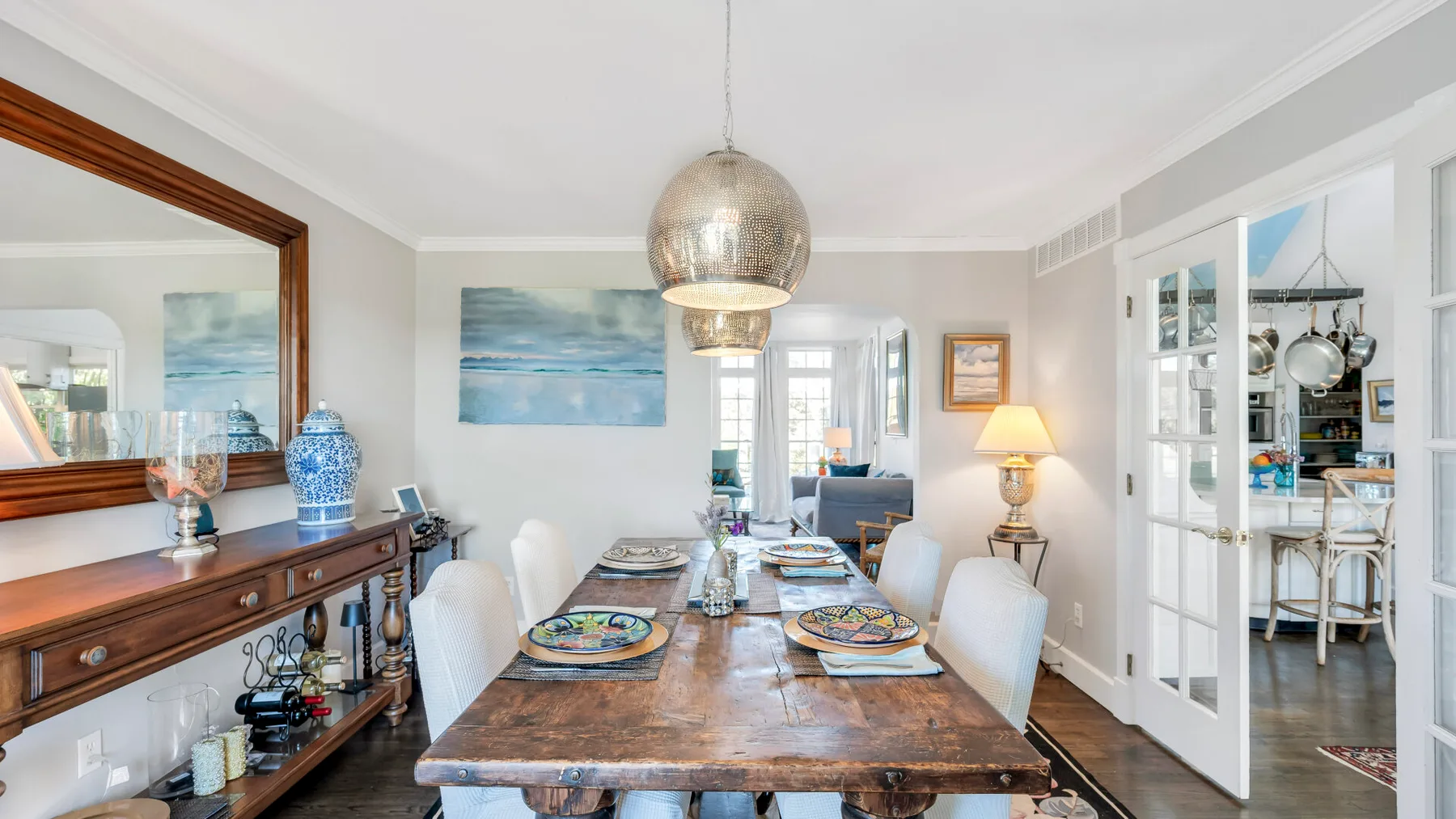 A dining area with a wooden table, place settings, and a pendant light.