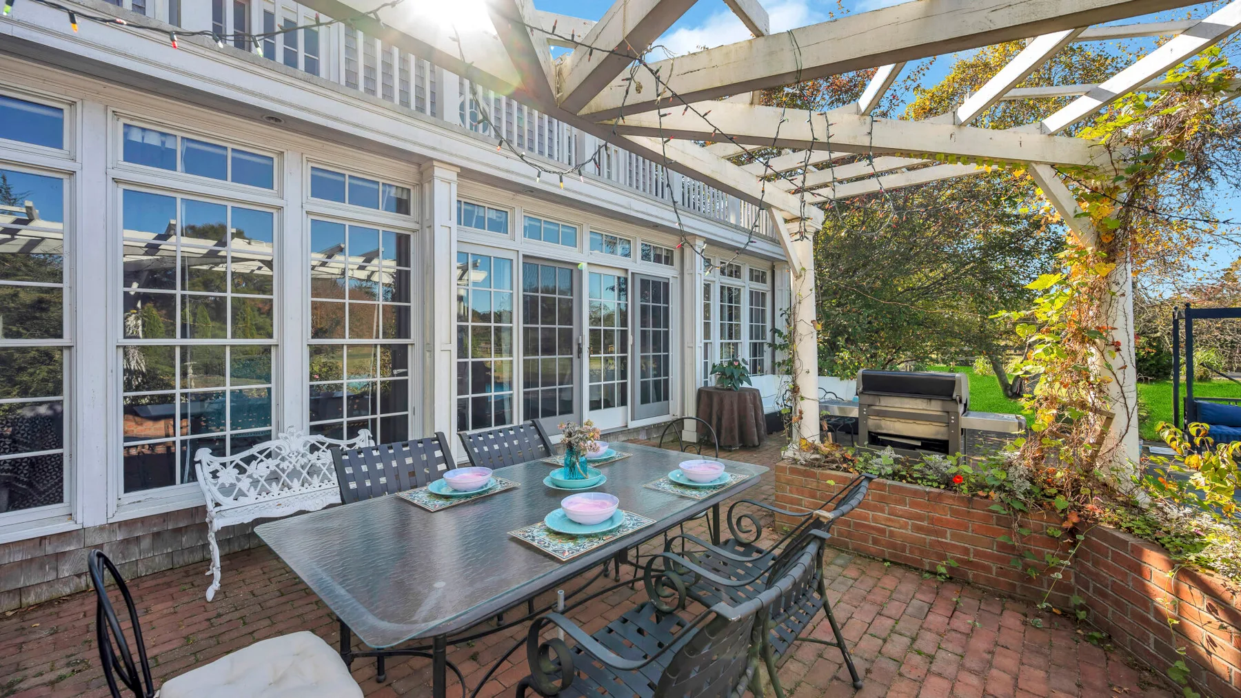 An outdoor patio with a dining table beneath a white pergola.