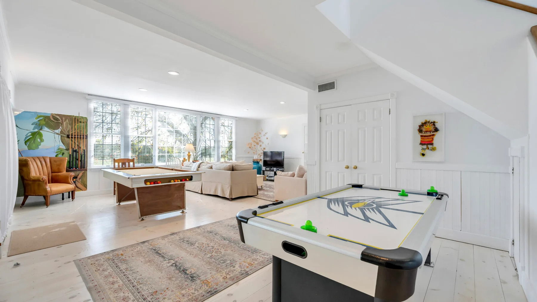 A bright living room with large windows and an air hockey table.