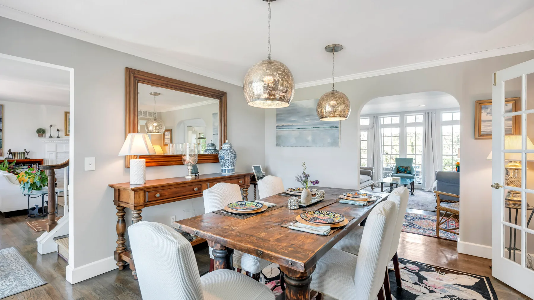 A dining room with a wooden table set beneath two pendant lights.