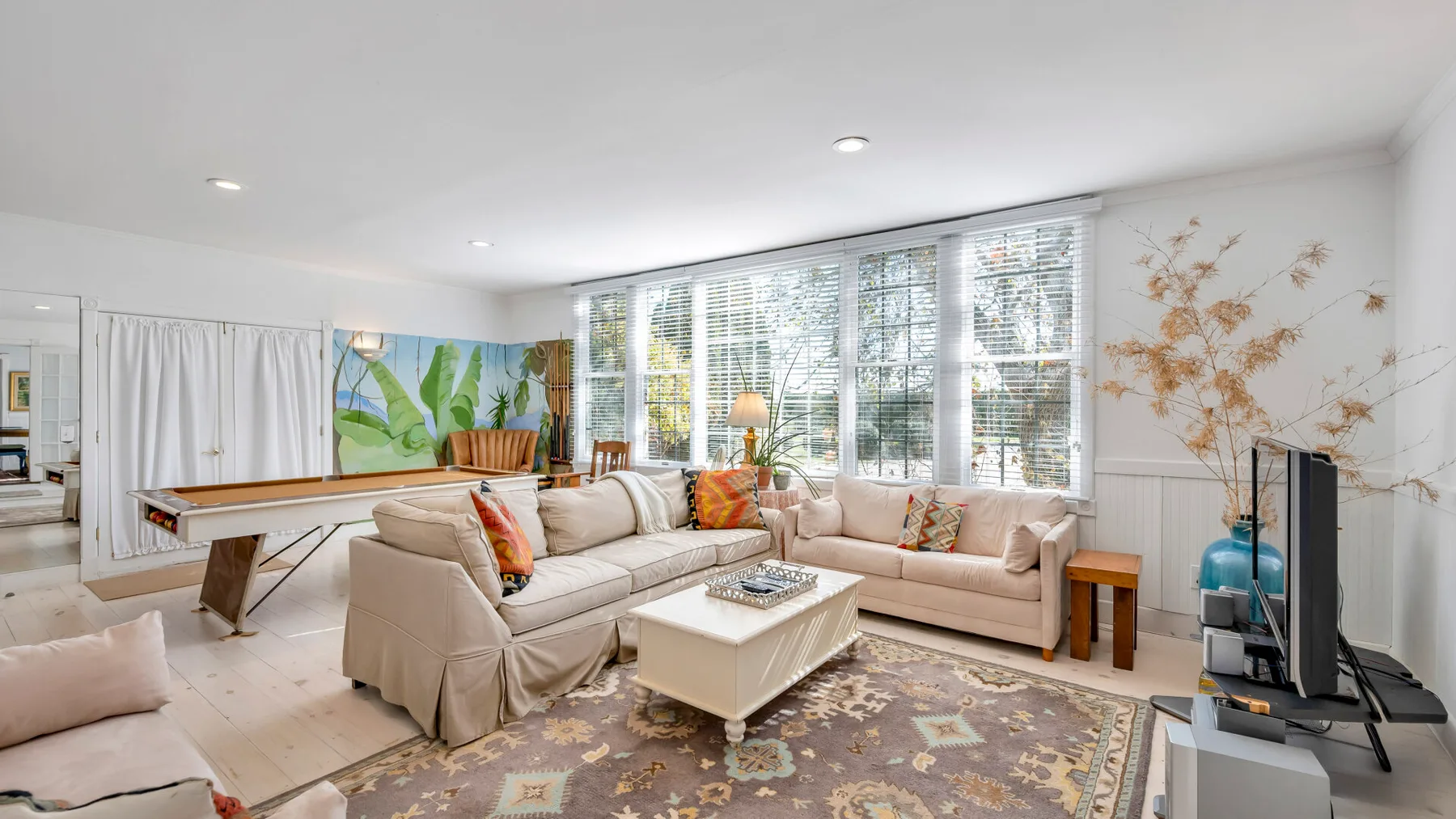 A bright living room with seating arranged around a coffee table beside large windows.