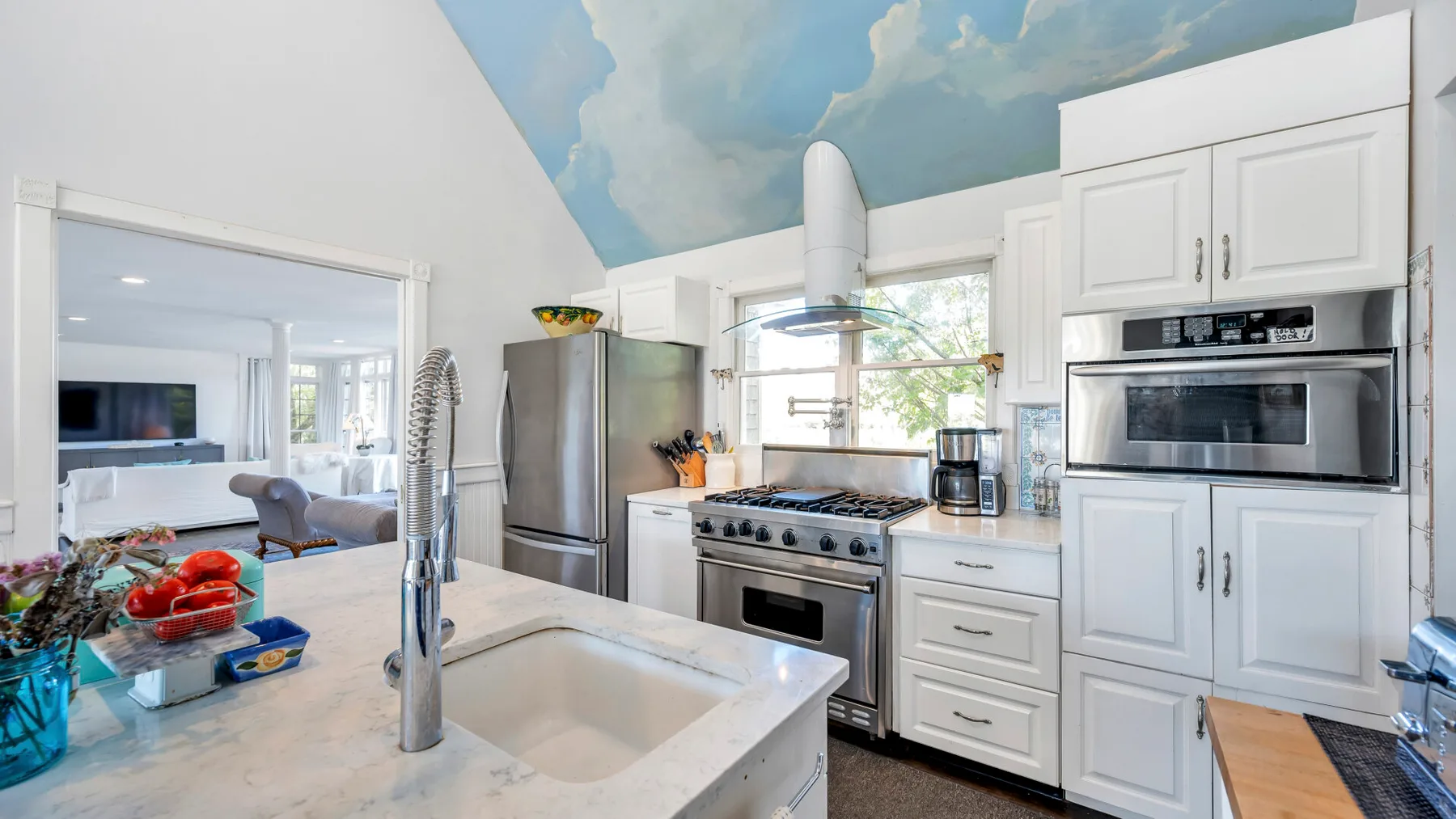 A bright kitchen features a central island, stainless steel appliances, and white cabinetry.