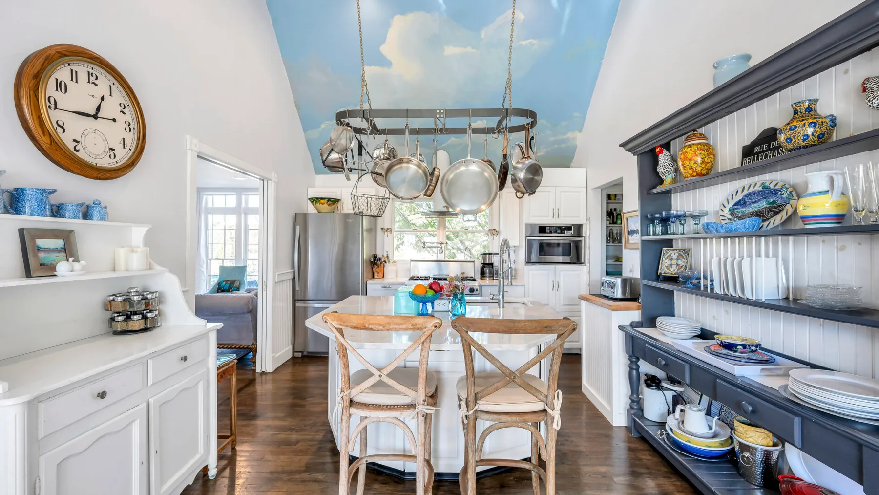 A bright kitchen and dining area with a table beneath hanging cookware.