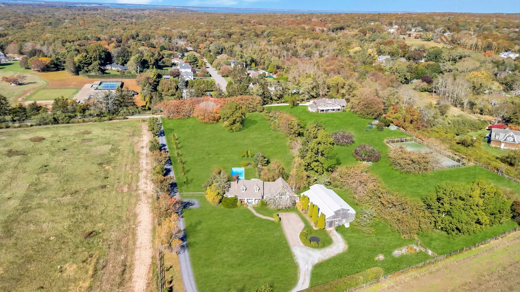 An aerial view of a house and landscaped grounds surrounded by trees.
