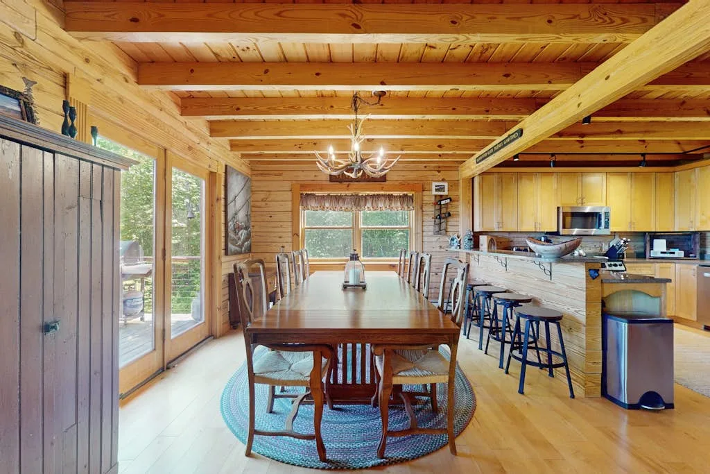A wood-paneled dining area with a long table and kitchen counter.