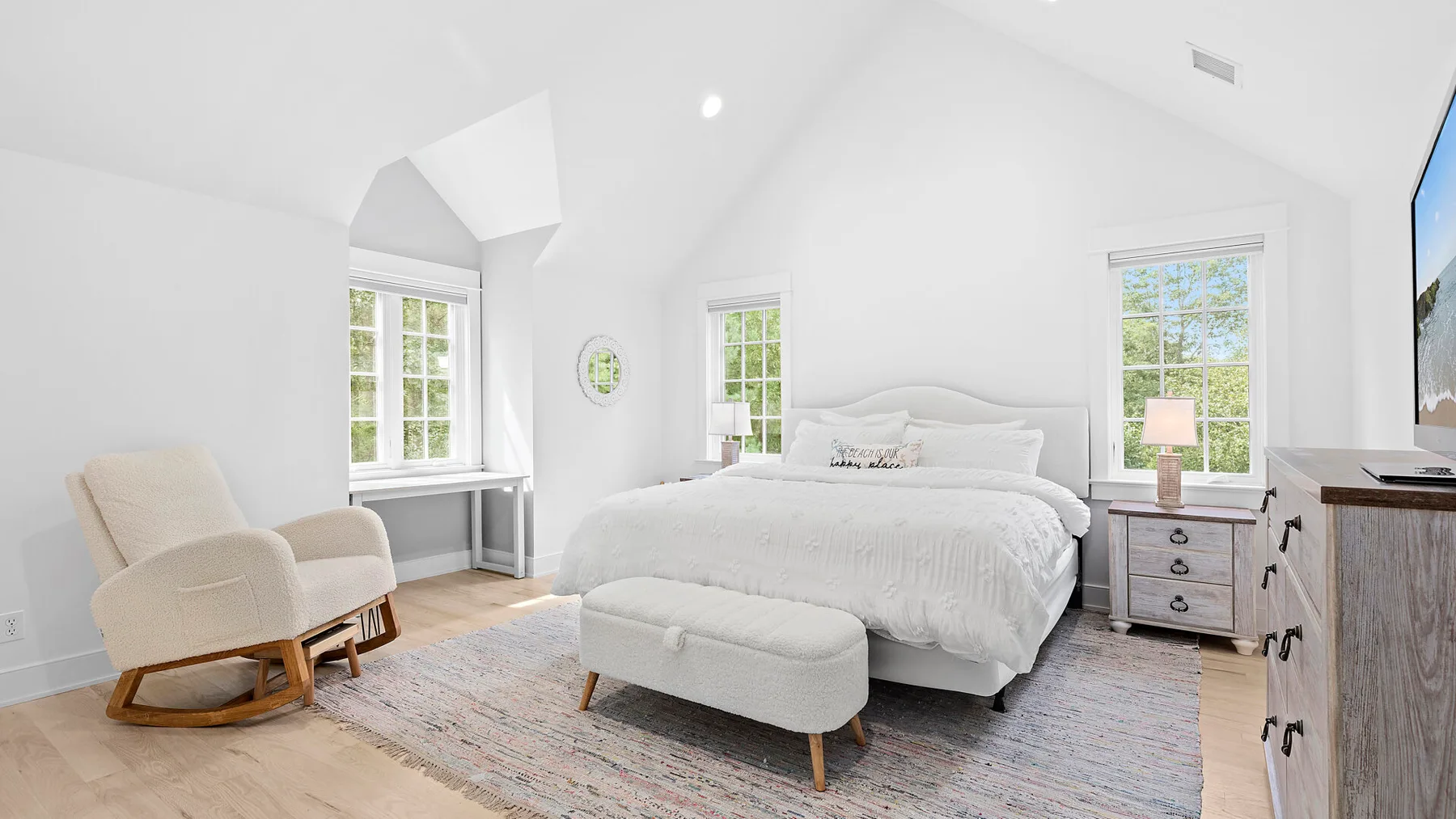 Un dormitorio luminoso con una cama, un banco tapizado y ventanas.