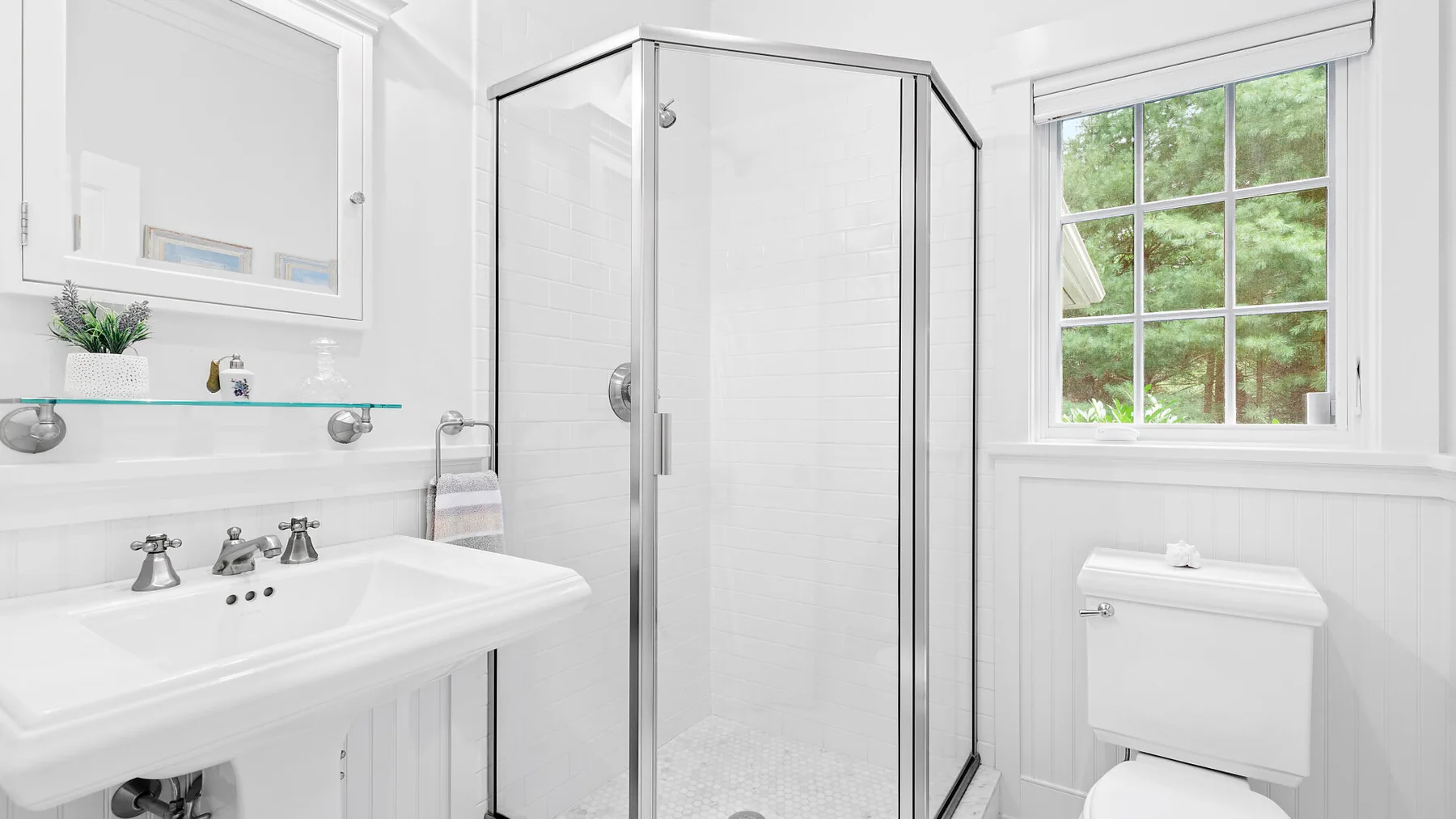 Un baño luminoso con ducha de vidrio, lavabo y ventana.
