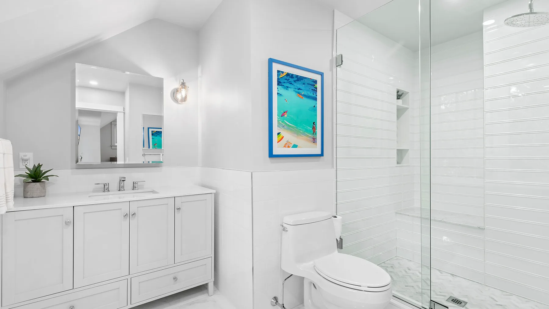 Un baño luminoso con un tocador blanco, inodoro y ducha de vidrio.