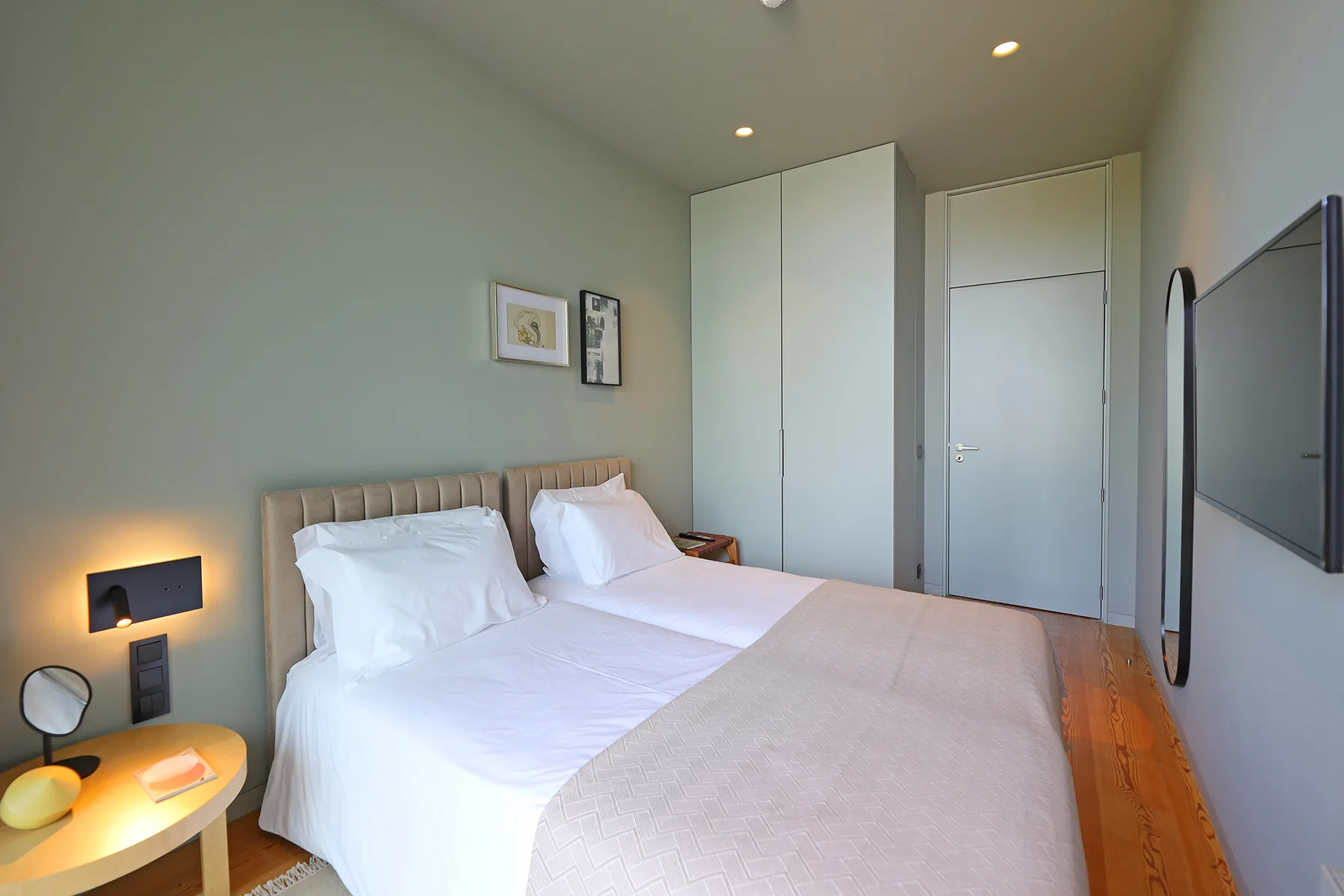 A bedroom with a neatly made bed, bedside table, and wall-mounted television.