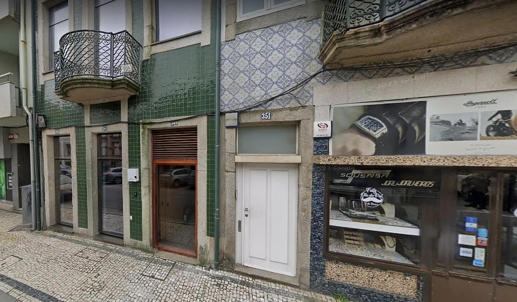 Street-level view of adjoining building facades, including a shopfront and a doorway.